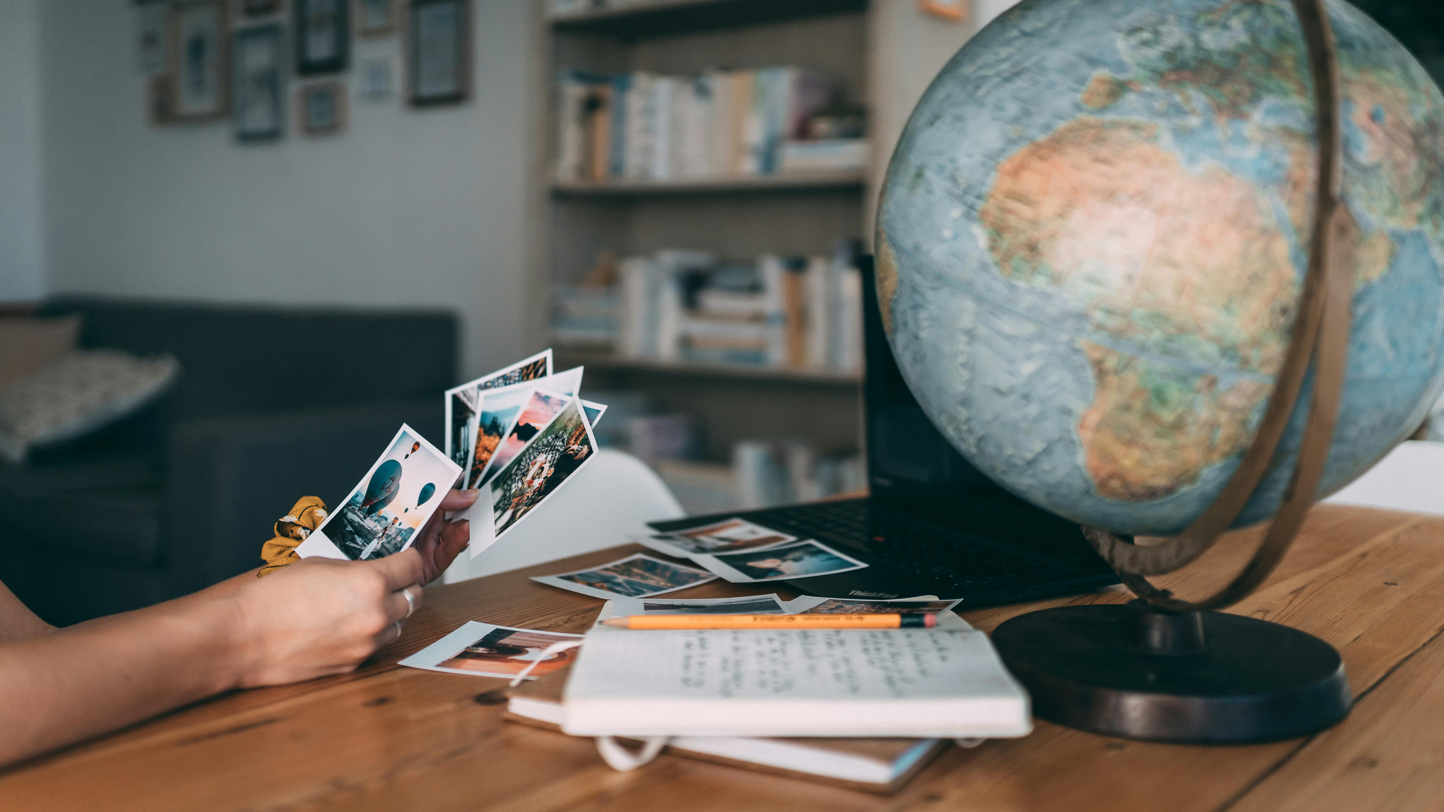 A person looking through photos, writing notes with a globe beside them